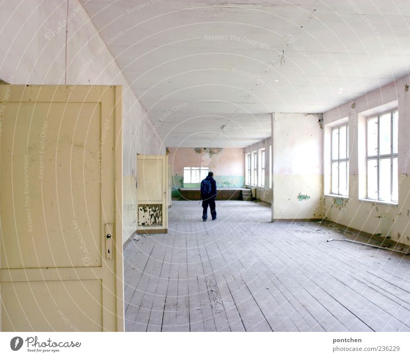 Rear view of a man standing in a large, dilapidated, old building flat. Wooden floorboards. Lost place Masculine 1 Human being House (Residential Structure)