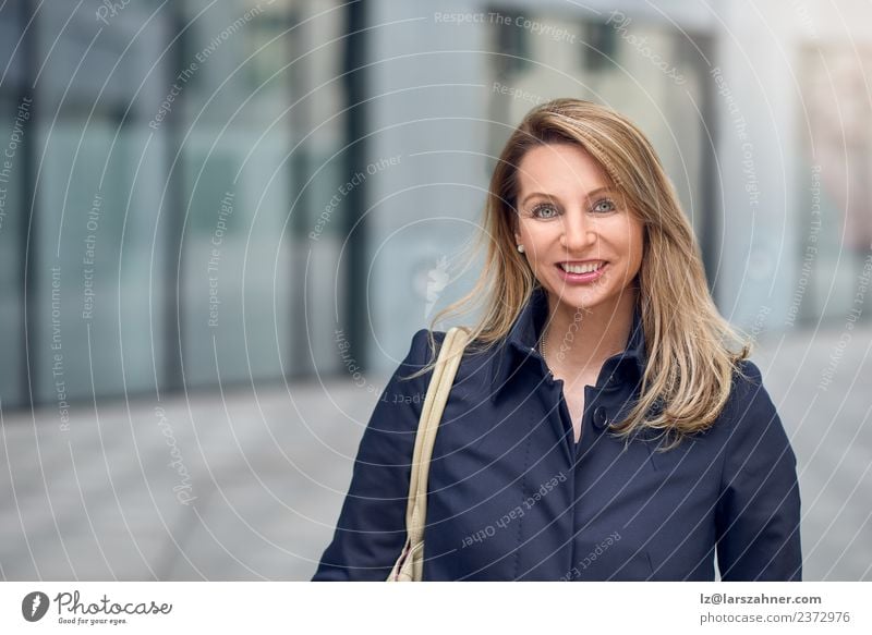 Pretty blond woman walking in an urban street Lifestyle Happy Beautiful Face Success Office Business Woman Adults 1 Human being 45 - 60 years Blonde Smiling