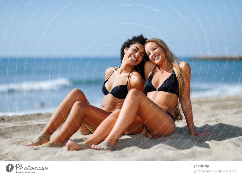 Two Women In Bikini Sitting On A Tropical Beach Sand A Royalty Free