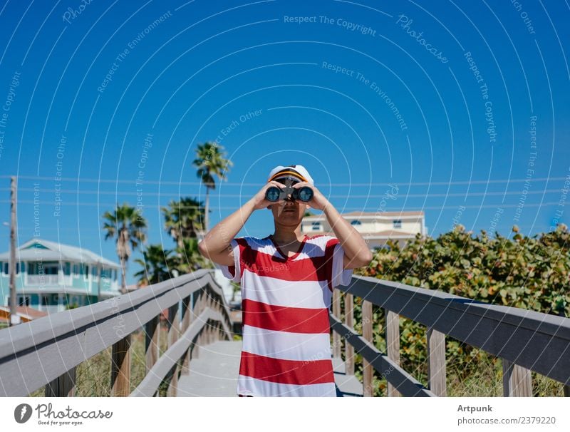 A young sailor looking through a pair of binoculars Binoculars Sailor Summer Beach Vacation & Travel Hat Captain Palm tree Tropical Jetty Plant Sand Tree Sky