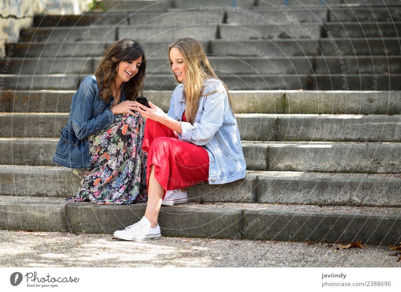 Two young women looking at an smart phone outdoors Lifestyle Shopping Joy Happy Beautiful Telephone PDA Technology Human being Feminine Young woman