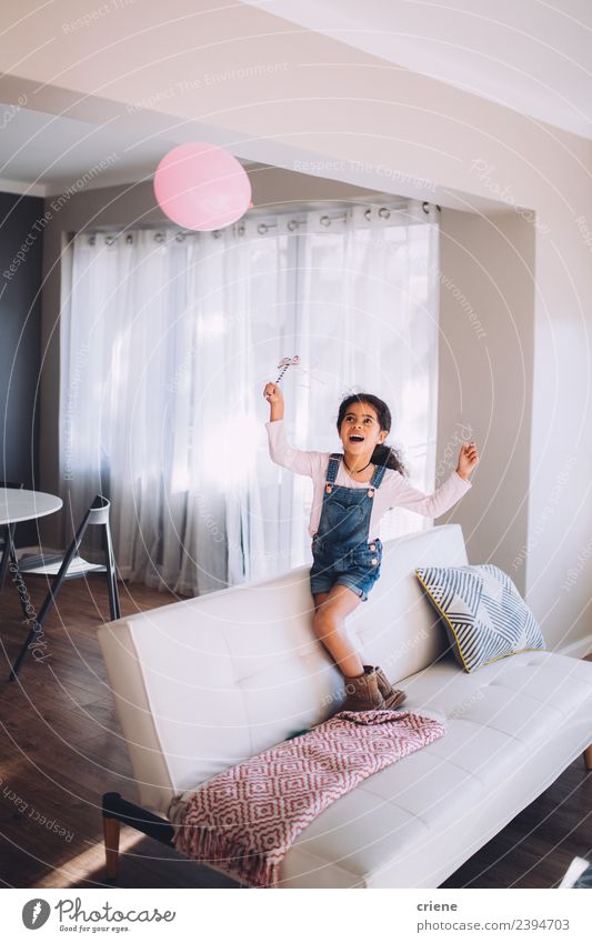 African happy girl playing with a balloon on couch Joy Happy Beautiful Playing Living room Child Infancy Balloon Smiling Happiness Small Cute kid people Home