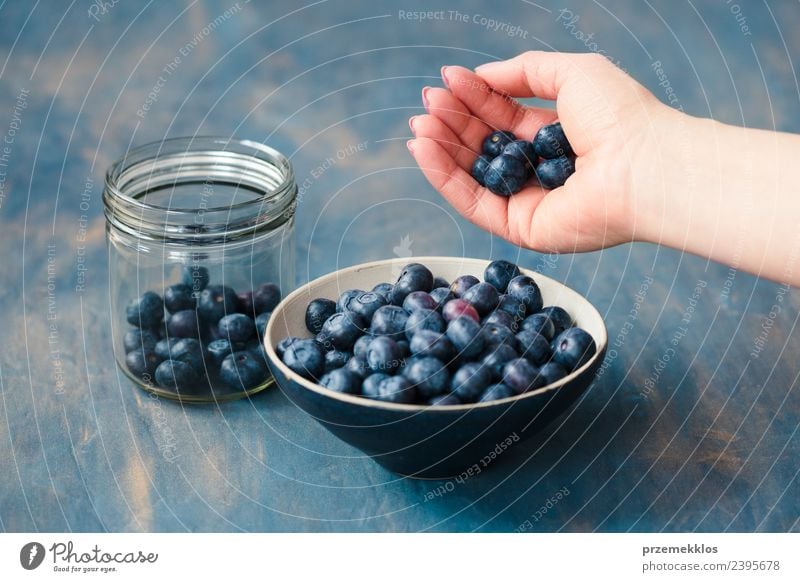 Woman putting fresh blueberries from a jar into a small bowl Fruit Nutrition Vegetarian diet Bowl Summer Table Adults Hand Nature Wood Fresh Delicious Natural