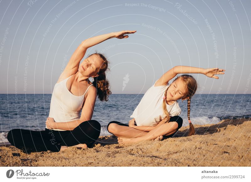 Mother and daughter doing yoga exercises on the beach. Lifestyle Joy Happy Body Wellness Harmonious Relaxation Meditation Leisure and hobbies Camping Summer