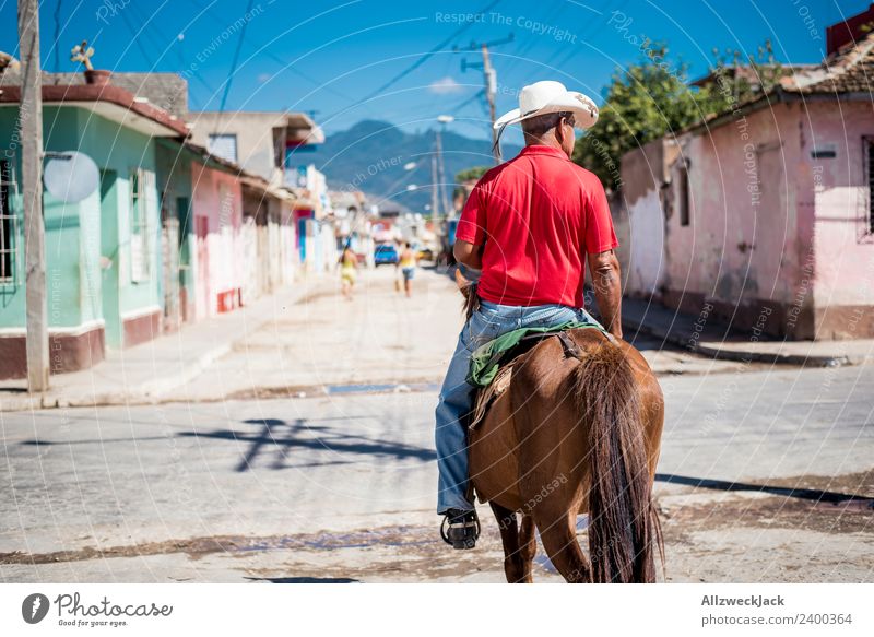 Man on a horse rides through Trinidad in Cuba Trinidade Socialism Old Historic Retro Old-school Old fashioned Exterior shot Day Summer Sun Blue sky Warmth