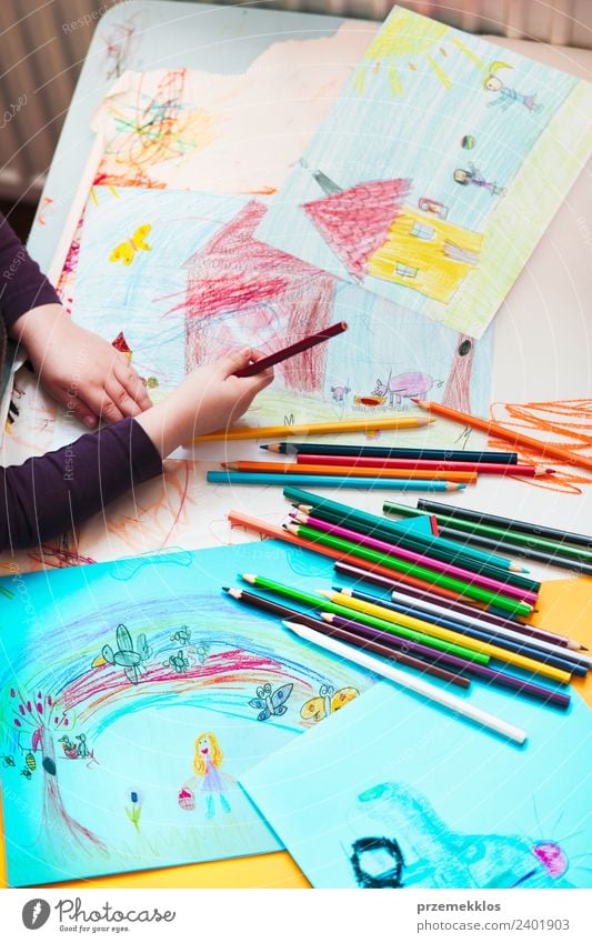 Crayons scattered on desktop filled with colorful drawings Lifestyle Joy Happy Handcrafts Table Education Kindergarten Child School Girl 1 Human being