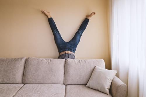 Adult man is standing on his head behind sofa in the room Lifestyle Health care Alternative medicine Athletic Fitness Leisure and hobbies Flat (apartment) Sofa