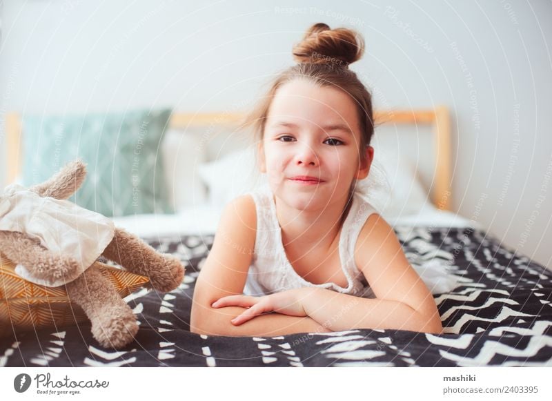 happy little child girl lying on her bed in the morning Lifestyle Joy Happy Hair and hairstyles Relaxation Sun Bedroom Child Toys Teddy bear Smiling Sleep Dream