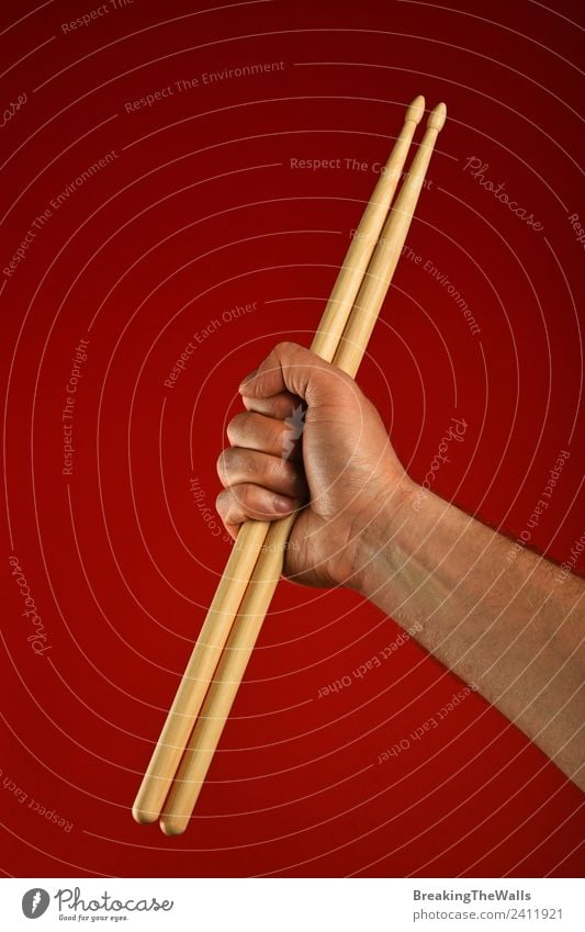 Man hand holding wooden drumsticks over red background Music Adults Hand 1 Human being Stage Shows Concert Musician Wood Red Fist Gesture Rocker Drummer Hold