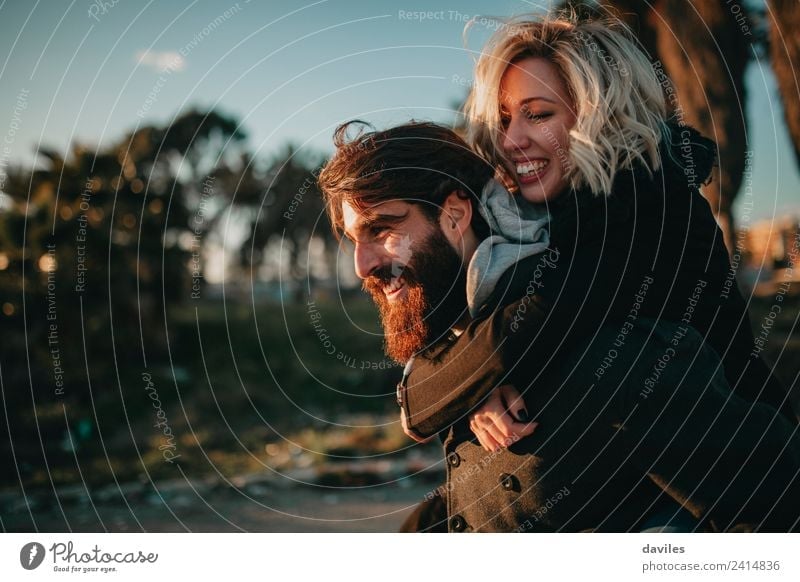 Smiling bearded man giving a piggy back to his girlfriend. Lifestyle Joy Leisure and hobbies Vacation & Travel Human being Young woman Youth (Young adults)