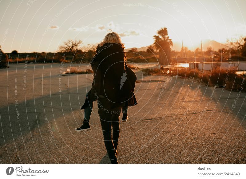 Man carrying in a piggyback way to his girlfriend on a deserted place at sunset. Lifestyle Playing Human being Young woman Youth (Young adults) Young man Couple