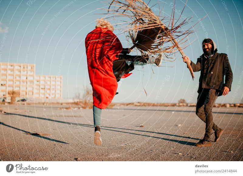 Cool woman and man playing and doing battles with plants and branches, outdoors at sunset. Lifestyle Joy Leisure and hobbies Playing Human being Young woman