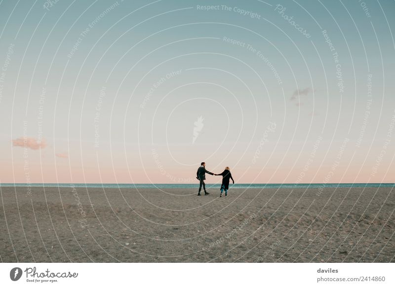 Young couple walking on the sand at a deserted beach, with the sea in the background, at dusk. Lifestyle Beach Ocean Winter Human being Young woman
