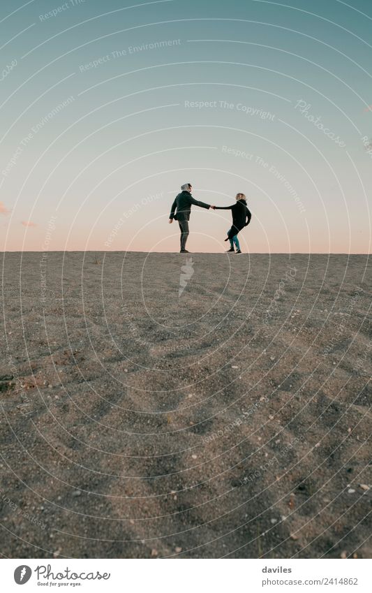 Lovely couple walking by the sand in the beach horizon. Lifestyle Joy Beautiful Beach Winter Human being Young woman Youth (Young adults) Young man Woman Adults