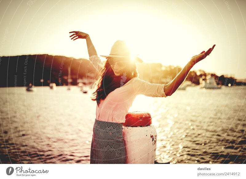 Smiling woman with sunglasses and hat raising arms happy with the sea in the background. Lifestyle Elegant Style Well-being Vacation & Travel Sun Beach Ocean