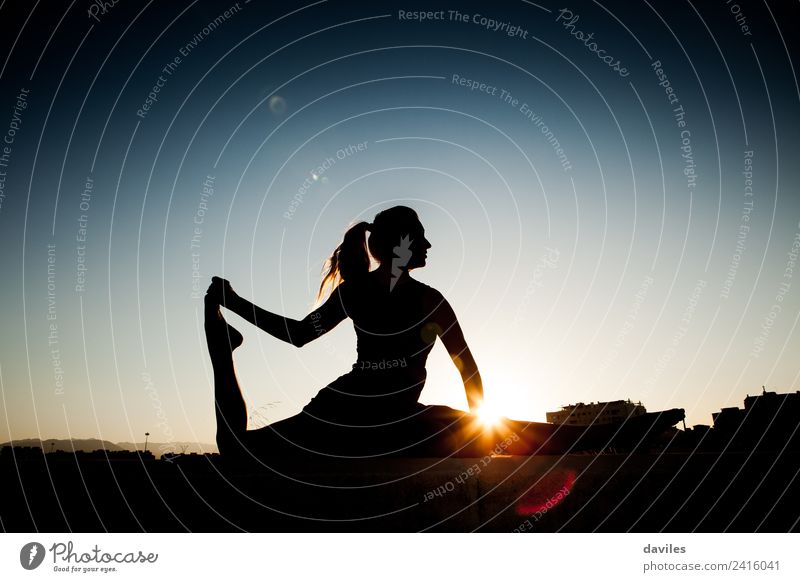 Woman silhouette during stretching session after fitness session. Backlight during sunset. Lifestyle Body Fitness Wellness Well-being Relaxation