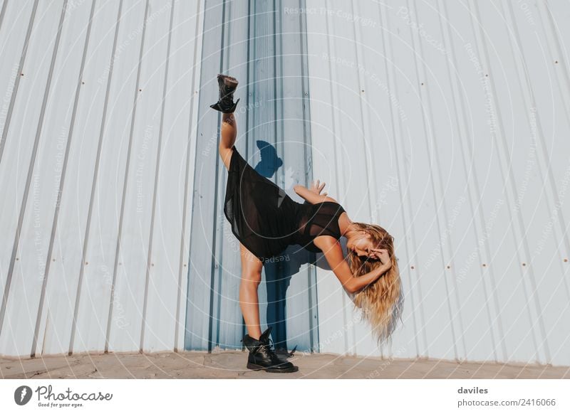 Blonde woman performing contemporary dance, raising up a leg, against a wall. Lifestyle Elegant Style Exotic Sports Human being Woman Adults
