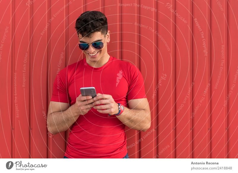 Man on red Reading Telephone Human being Adults Sunglasses Brunette Touch Smiling Red 20-25 years old 20s 30 years old attractive door Latin Latin American