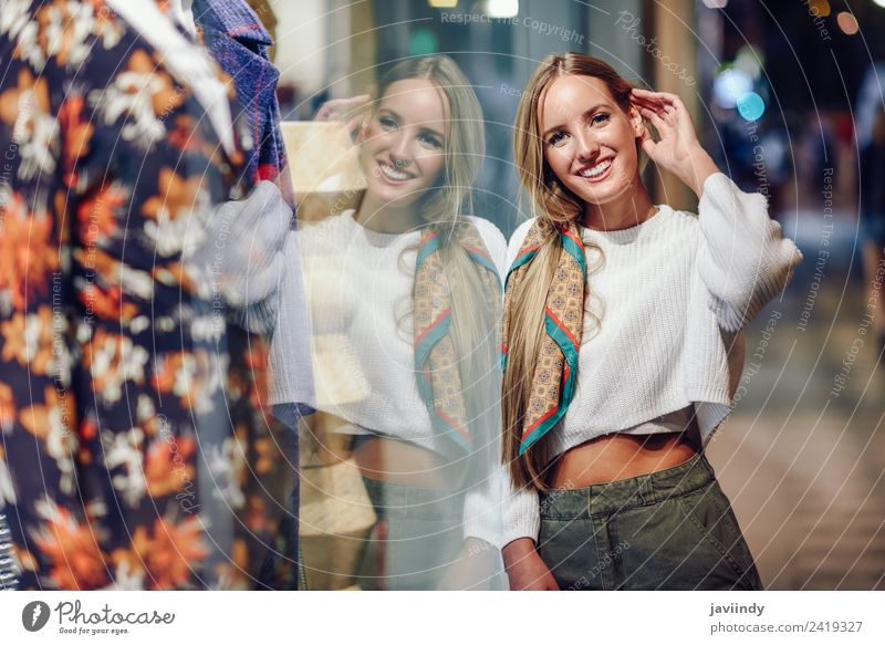 Blonde girl wearing white sweater smiling in the street with defocused city lights at the background Lifestyle Shopping Style Happy Beautiful
