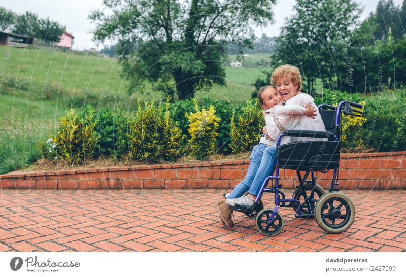 Granddaughter hugging grandmother in wheelchair Lifestyle Happy Health care Relaxation Garden Human being Woman Adults Grandmother Family & Relations Nature