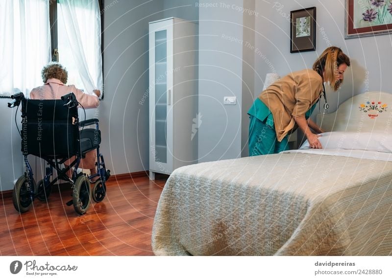 Caregiver making bed of elderly patient in nursing home Lifestyle Health care Illness Medication Relaxation Chair Bedroom Doctor Hospital Human being Woman