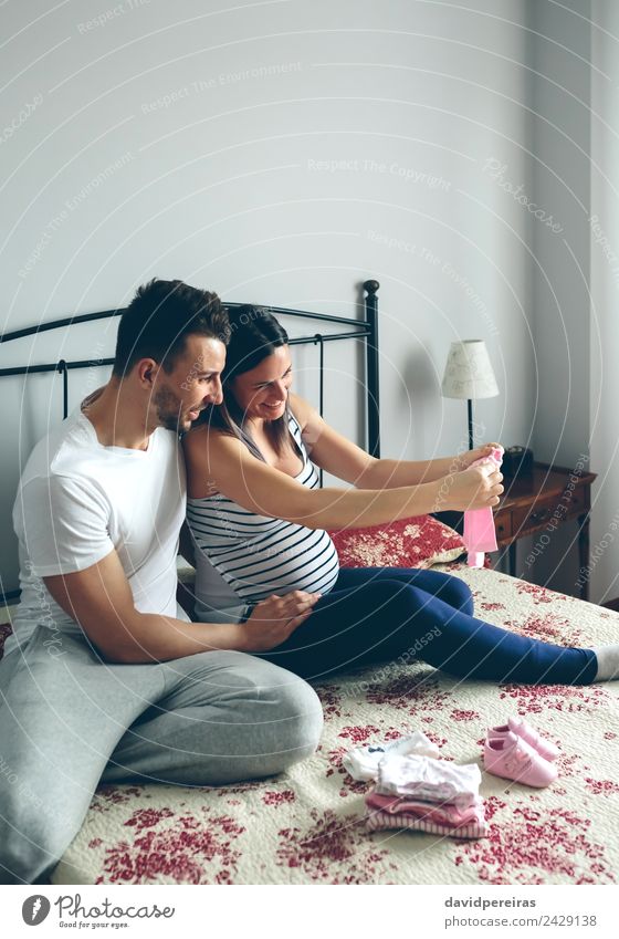 Man and pregnant woman looking baby clothes Shopping Beautiful Bedroom Human being Baby Woman Adults Mother Father Family & Relations Couple Partner Clothing