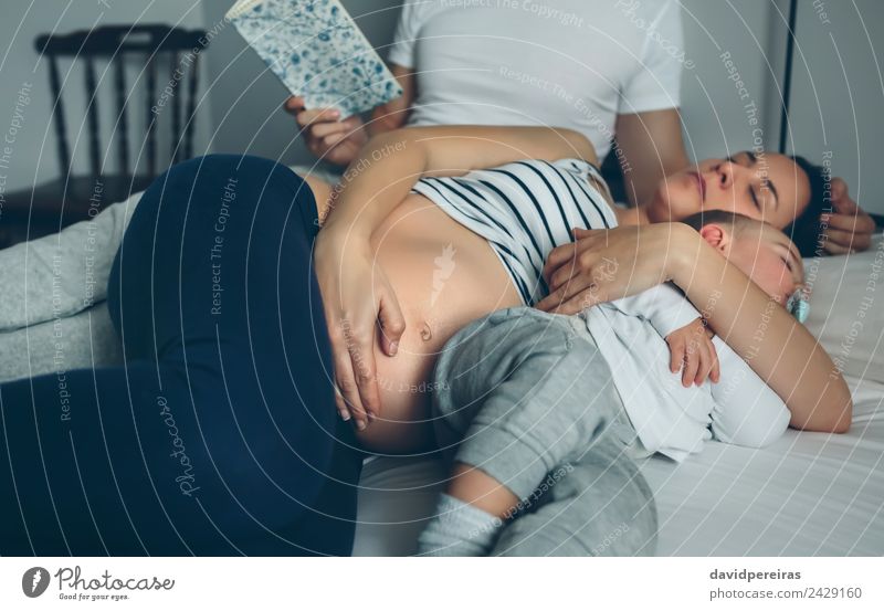 Man reading with pregnant wife and son sleeping Beautiful Relaxation Reading Bedroom Child Human being Baby Toddler Woman Adults Parents Mother Father