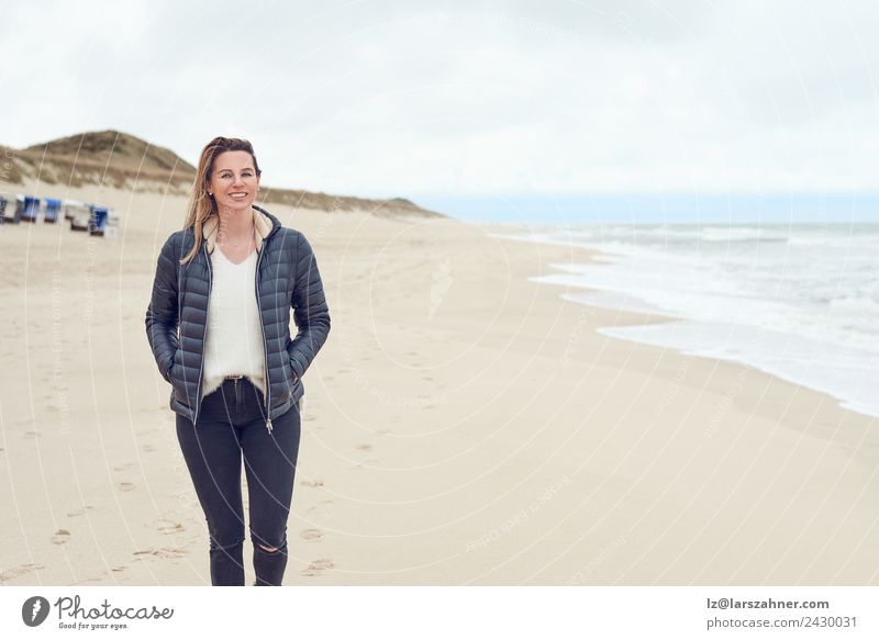Woman walking on a beach on a cloudy day Leisure and hobbies Freedom Beach Ocean Adults 1 Human being 45 - 60 years Sand Clouds Autumn Coast North Sea