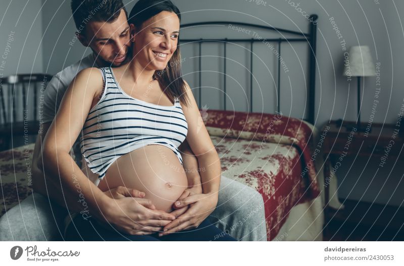 Pregnant woman embraced by her husband Bedroom Human being Baby Woman Adults Man Parents Mother Father Family & Relations Couple Partner Hand Touch Smiling Love