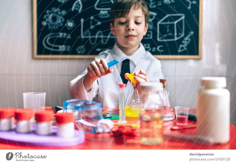 Serious little boy playing with chemical liquids Bottle Happy Playing Flat (apartment) Table Science & Research Child Classroom Blackboard Laboratory