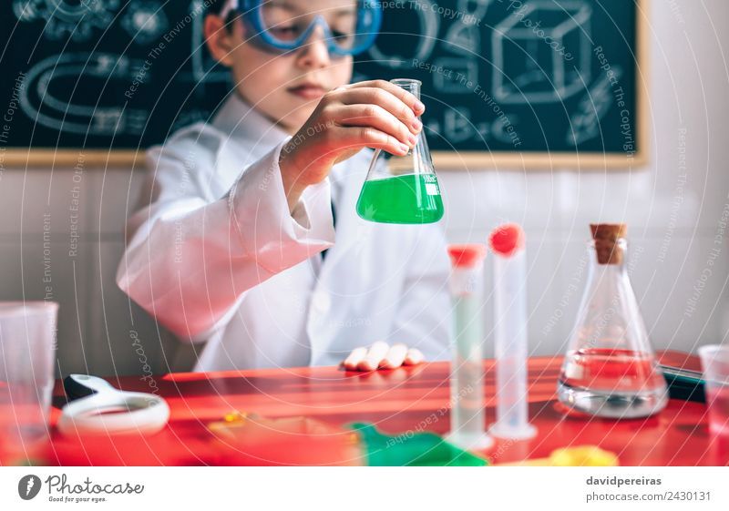 Little boy scientist with glasses holding flask against of blackboard Bottle Playing Flat (apartment) Table Science & Research Child Classroom Blackboard