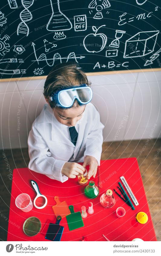 Kid playing with chemical liquids over table Bottle Happy Playing Flat (apartment) Table Science & Research Child Classroom Blackboard Laboratory Human being