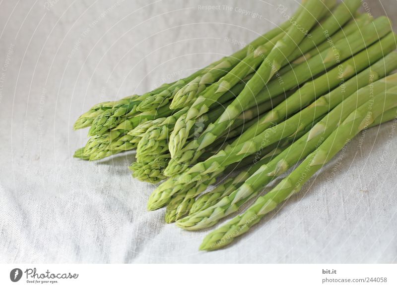 Portion of asparagus bunch with green, fresh, juicy asparagus, from fresh, local harvest, lies in heaps, bundles on a white cloth made of linen. Food Vegetable