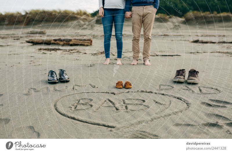 Mum, dad and baby written on the sand with the parents behind Lifestyle Beach Winter Human being Baby Woman Adults Man Parents Mother Father Family & Relations