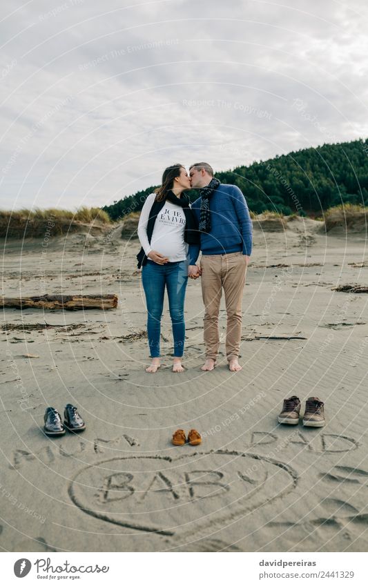 Mum, dad and baby written on the sand with the parents kissing Lifestyle Beach Winter Human being Baby Woman Adults Man Parents Mother Father Family & Relations