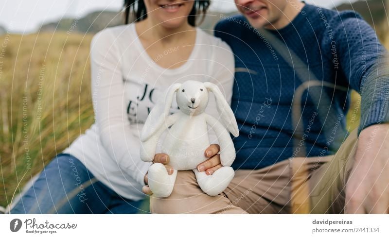Couple showing a stuffed bunny Lifestyle Happy Human being Baby Woman Adults Man Father Family & Relations Grass Meadow Teddy bear Smiling Love Wait Authentic