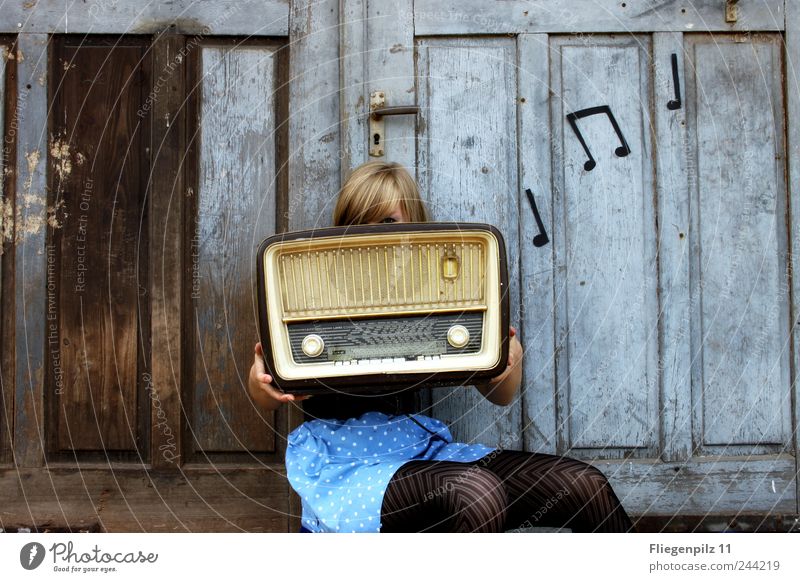 retro styled young woman poses with radio in front of old wooden gate. Music  notes. tube radio - a Royalty Free Stock Photo from Photocase