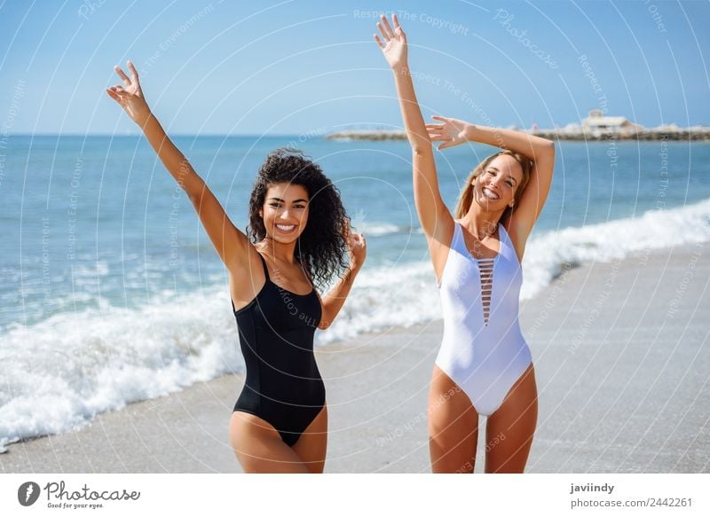 Two young women with beautiful bodies in swimwear on a tropical beach  taking a walk on shore. - a Royalty Free Stock Photo from Photocase