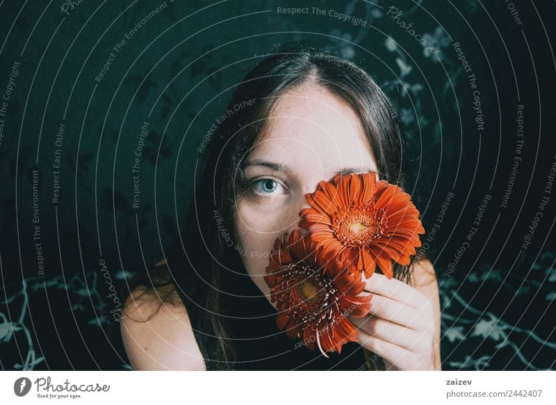 a girl with blue eyes and long hair covering herself with a gerbera flower Lifestyle Beautiful Face Relaxation Calm Human being Woman Adults Plant Flower