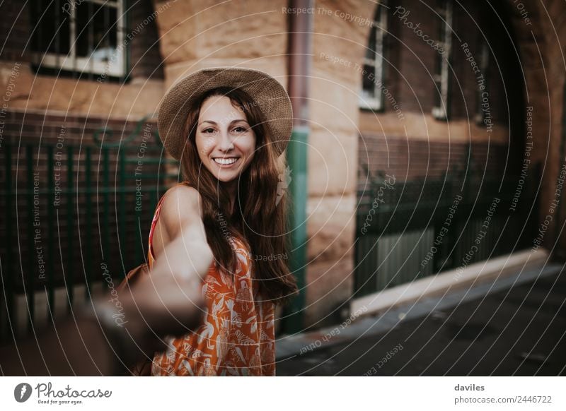 Smiling girl with a hat pulling from her boyfriend hand in the street to take a walk. Lifestyle Joy Leisure and hobbies Vacation & Travel Trip City trip