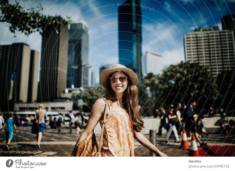 Cute smiling woman with hat and sunglasses walking in the street with Sydney cityscape in the background. Lifestyle Shopping Style Joy Beautiful