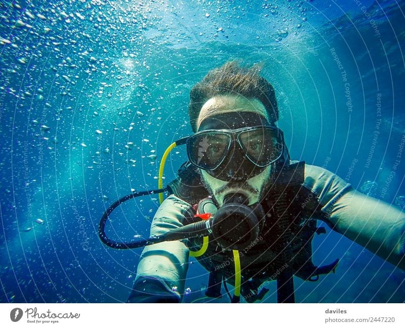 Man with scuba diving equipment diving in the sea and looking at camera with blue water background. Lifestyle Exotic Joy Leisure and hobbies Vacation & Travel