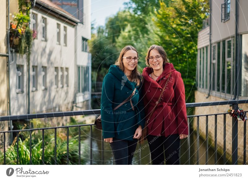 happy twin sisters stand on a bridge in Erfurt and laugh into the camera Lifestyle Style Joy luck Human being Feminine Young woman Youth (Young adults)