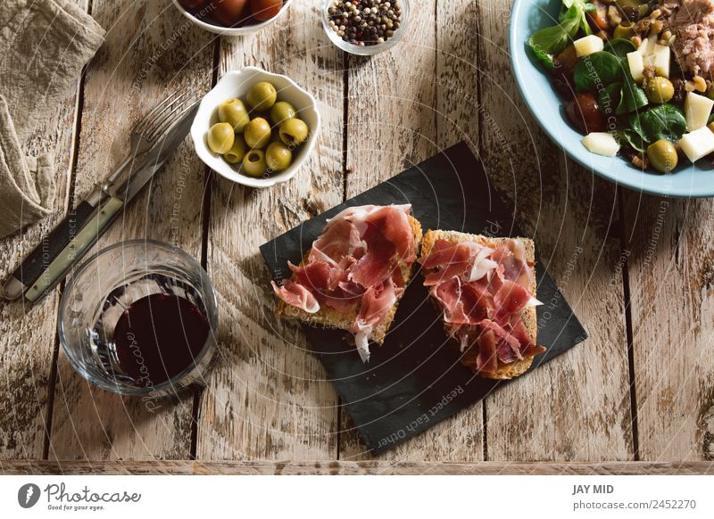 Delicious appetizer of spanish ham and salad Ham Spanish Bread Toast Appetizer cookery Cut Sandwich iberic Pork Lunch Meal Salad Dinner stuffed olives Rustic