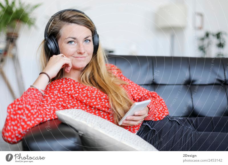 Happy woman listening to music wearing headphones Lifestyle Joy Beautiful Relaxation Calm Leisure and hobbies Playing Sofa Music Telephone PDA Technology