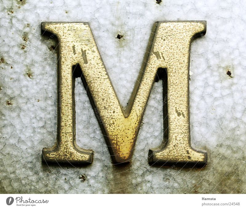 Golden M Letters (alphabet) Serif Obscure Metal Light from side Embossing punching