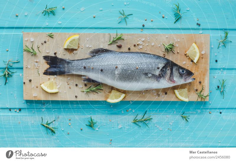 Sea bass with spices on kitchen table and blue wooden background Seafood Herbs and spices Eating Dinner Diet Table Restaurant Animal Wood Write Fresh Delicious
