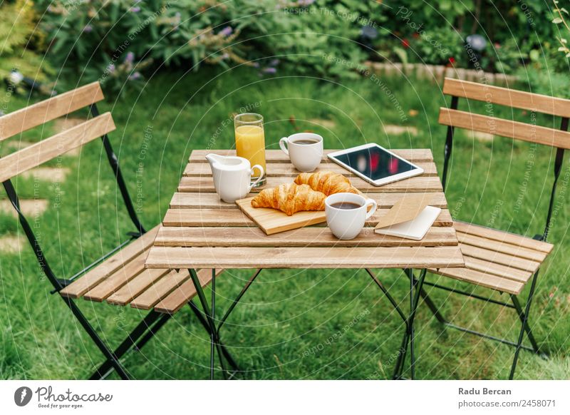 Morning Breakfast In Green Garden With French Croissant, Coffee Cup, Orange Juice, Tablet and Notes Book On Wooden Table Background picture Summer White Food