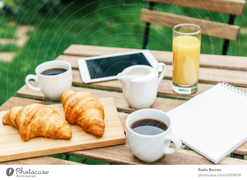 Morning Breakfast In Green Garden With French Croissant, Coffee Cup, Orange Juice, Tablet and Notes Book On Wooden Table Background picture White Food Drinking
