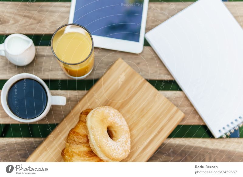 Morning Breakfast In Green Garden With French Croissant, Donuts, Coffee Cup, Orange Juice, Tablet and Notes Book On Wooden Table Background picture White Food